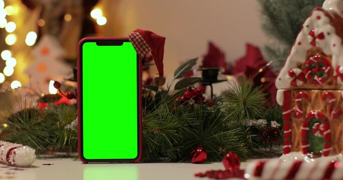 IPhone Xs Max In Vertical Orientation With Green Screen On A Background Of Christmas Tree And Holiday Lights. Santa Claus' Hat On Top. Online Store, App Promo, Ads. Zoom In Shot