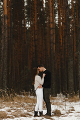 Young man and woman kissing in the winter forest. With the place for your text. Love, relationship, winter holidays. Winter couple photo ideas