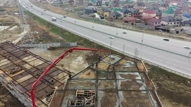 Construction site of residential complex building using self propelled concrete pump against highway and town aerial view