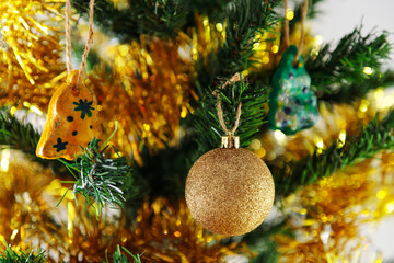 A golden toy hangs on the tree. Tinsel, new year, shine of garlands.