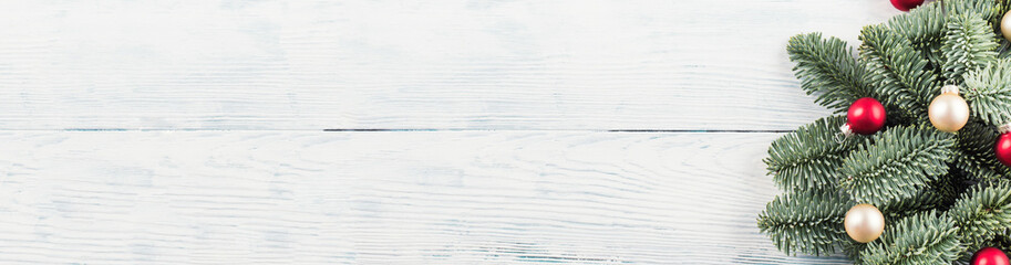 Christmas spruce branches with red and golden decor on wooden wood table. Festive holiday background web banner