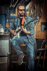 Guitarist is playing on electric guitar in a musical instrument shop.