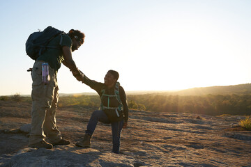 Man helps woman take step on mountain