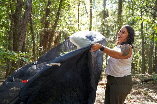 Woman sets up camping gear at campsite