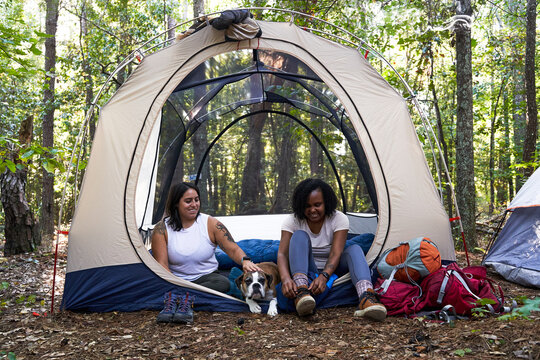 Diverse female friends camping in tent in the woods