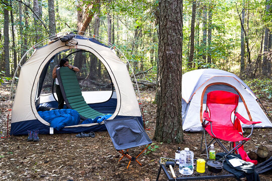 Woman blows up pad for sleeping bag in camping tent
