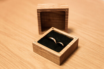 two wedding rings in a wooden square shaped box bride and groom close up