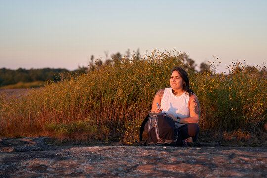 Hispanic woman writing in journal in nature