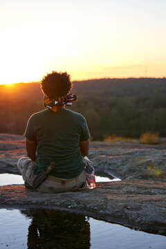 Black man meditates on mountain outdoors
