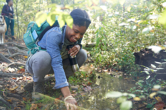 Black female botanist examines plants on trail