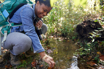 Black female botanist examines plants on trail