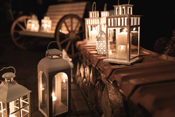 multiple white lanterns with candles inside at night 
