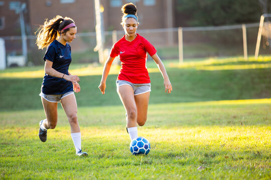 Teenage girl soccer players running after ball