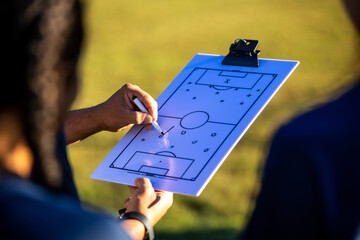 Teenage soccer coach teaches plays with female team
