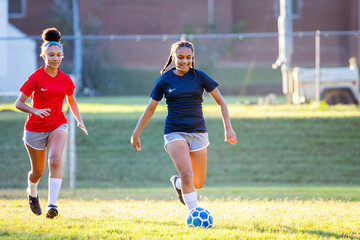 Teenage girl soccer players running after ball