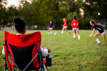 Supportive mom watches daughters play soccer