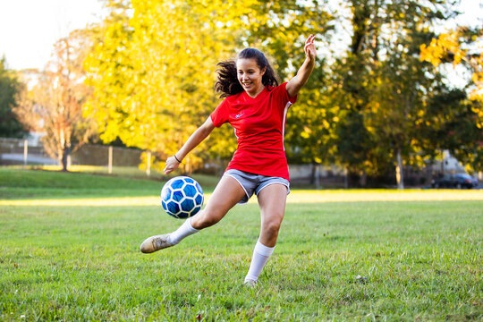 Latin female soccer player kicking ball