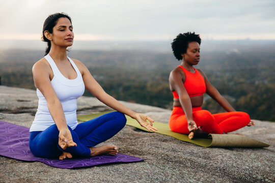 Diverse friends breathing and meditating together in park