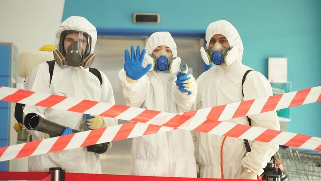 Woman in protective hazmat suit stops, does not let to enter building, don't allow. During coronavirus epidemic.