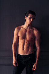 Frontal portrait of a fit, athletic young man on dark grey background.