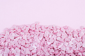 the pink surface is covered with lots of heart-shaped pink confetti as a romantic background composition