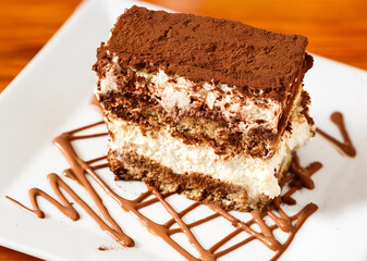 Tiramisu dessert in a white plate with chocolate 