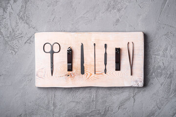 Set of manicure, pedicure tools and accessories on wooden board, stone concrete background, top view