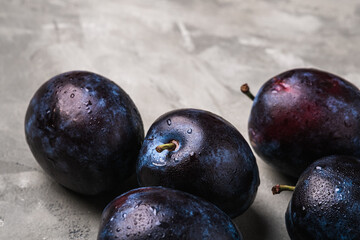 Fresh ripe plum fruits with water drops on stone concrete background, angle view macro