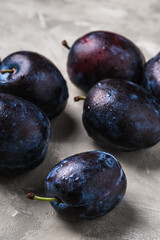 Fresh ripe plum fruits with water drops on stone concrete background, angle view macro