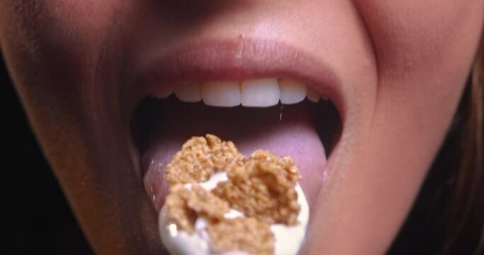 Young woman mouth eating yogurt with breakfast cereal