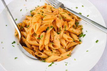Tuna noodles sprinkled with cheese and green parsley. Traditional Greek dish.