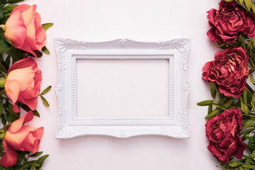 red dead and living roses lie on a white background, in the middle is a photo frame
