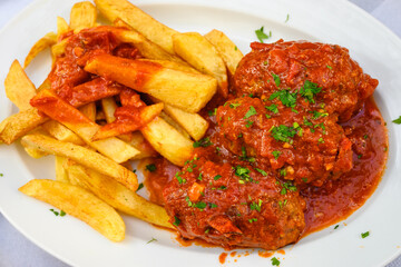 Minced cutlets in tomato sauce served with fries. Traditional Greek dish.