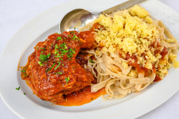 Stewed rooster in tomato sauce, served with homemade pasta and cheese. Traditional Greek dish