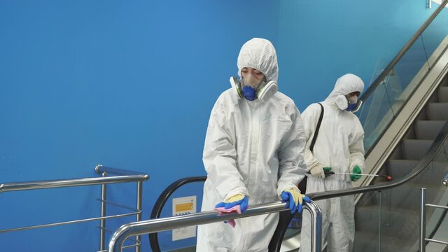 Disinfectors in suits disinfecting buildings of coronavirus with the sprayer, clean the territory.