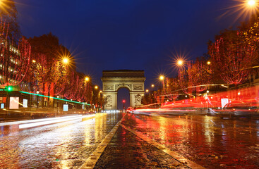 The Triumphal Arch and Champs Elysees avenue illuminated for Christmas at rainy night ,Paris,...