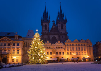 Fototapeta na wymiar Christmas tree and the Old Town Square in Prague, Czech Republic, covered by fresh snow. No Christmas markets organized in 2020 due to Covid-19