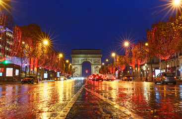 Fototapeta premium The Triumphal Arch and Champs Elysees avenue illuminated for Christmas at rainy night ,Paris, France.
