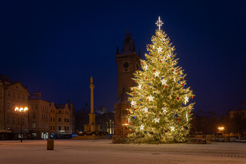 Fototapeta na wymiar Christmas tree and the Old Town Square in Prague, Czech Republic, covered by fresh snow. No Christmas markets organized in 2020 due to Covid-19