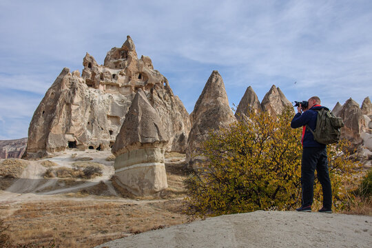 A man with a camera takes pictures of a beautiful cave complex in Cappadocia. Turkey