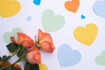 on a white background hearts made of paper of different colors and delicate roses
