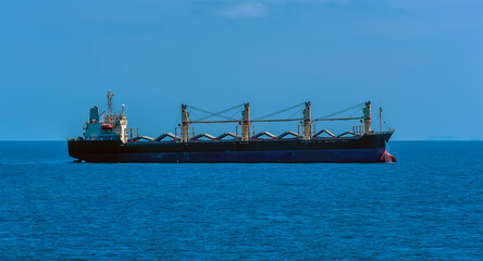 A side view of lightly laden bulk carrier vessel at sea approaching the Singapore Straits in Asia in summertime