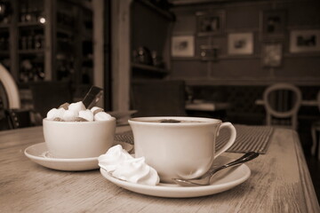 Vintage Cup Of Tea With Meringue and Sugar. Blurry Restaurant Background Sepia Toned Image. Cafe Scene.