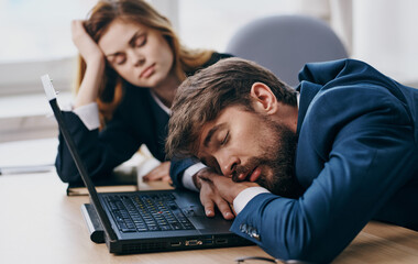 Work colleagues asleep at the desk in front of the laptop fatigue rest