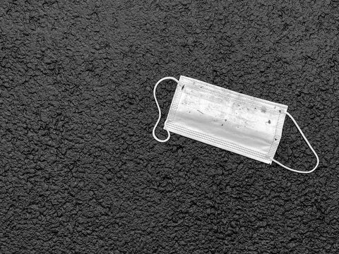 Plastic Face Mask Thrown Away On A Oavement After Use. Black And White. No People. Copy Space.