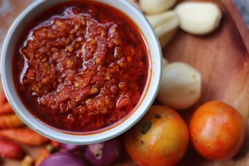Indonesian traditional extra spicy chili sauce with ingredients, chilies, onions, garlic, salt, and tomatoes