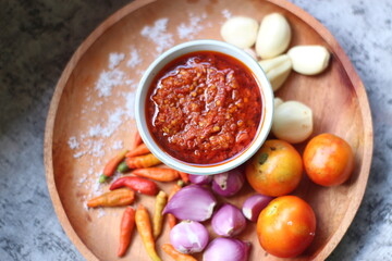 Indonesian traditional extra spicy chili sauce with ingredients, chilies, onions, garlic, salt, and tomatoes