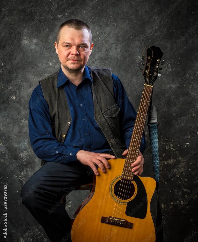 Wall mural mature musician plays acoustic guitar emotional studio portrait.