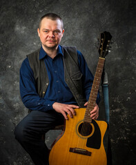 Mature musician plays acoustic guitar emotional studio portrait.