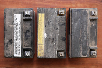 Three motorcycle gel batteries, two used, one in working order. View from above.
